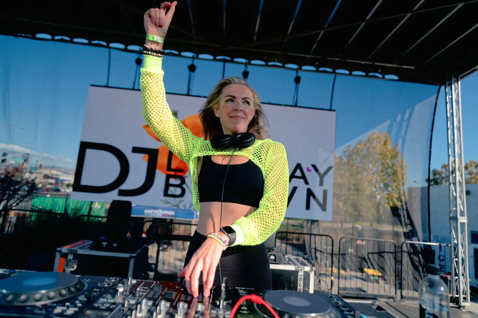 DJ Lyndsay Brown on an outdoor festival stage in front of her own banner