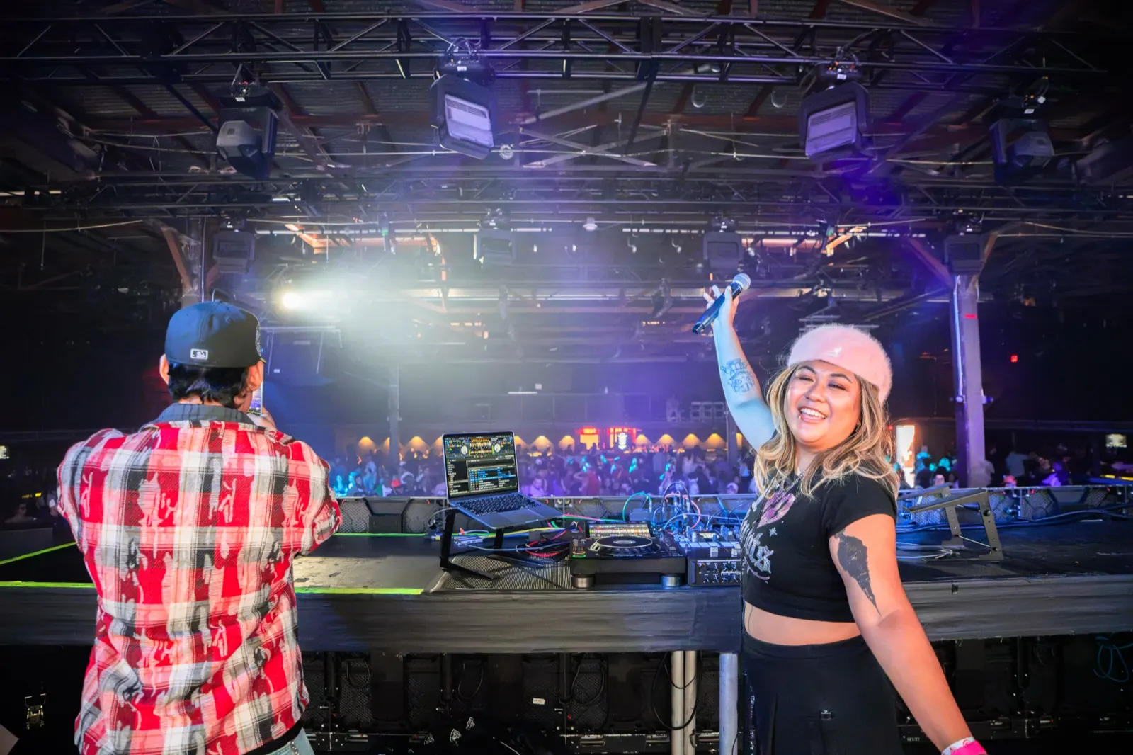 DJ Trixy raising the microphone to the crowd from the DJ booth